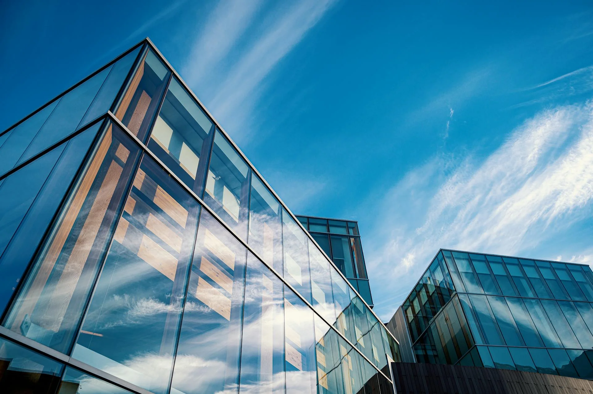 Modern glass office building with reflections of the sky and clouds, symbolizing transparency, innovation, and a forward-thinking approach in financial services aimed at driving business growth and success.